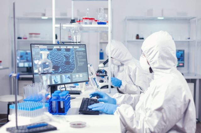 Chemist in ppe suit typing on keyborad